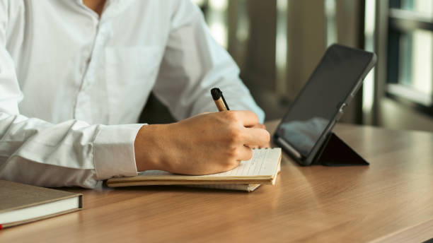 istock businessman working at work table,home office desk background, checklist writing planning investigate enthusiastic concept. Male hand taking notes on the notepad. 1991690755