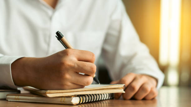istock businessman working at work table,home office desk background, checklist writing planning investigate enthusiastic concept. Male hand taking notes on the notepad. 1991691236