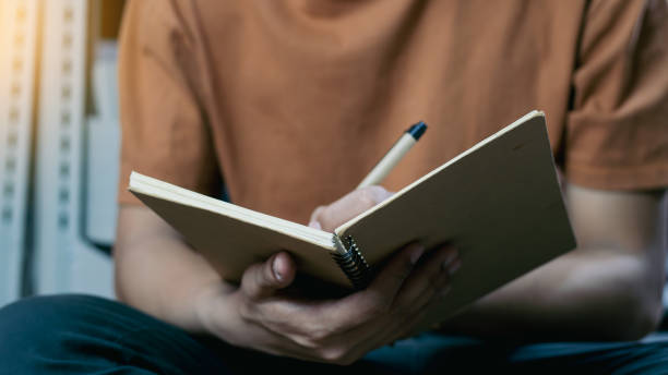 istock Male hand taking notes on the notepad in library. Handwriting. Creative writing. Inscription or recording of signs and symbols. 1991694624
