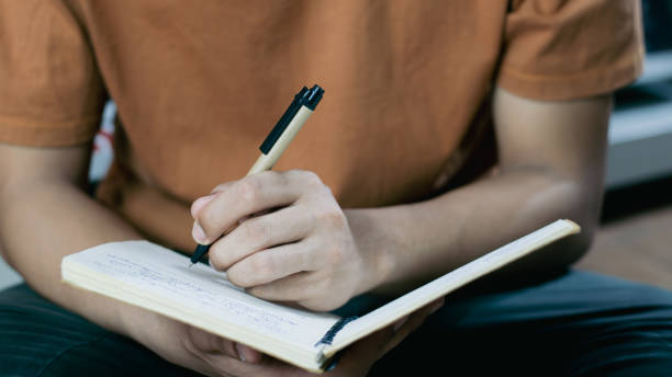 istock Male hand taking notes on the notepad in library. Handwriting. Creative writing. Inscription or recording of signs and symbols. 1991694632