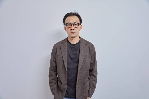 istock Handsome Asian businessman in suit, look at camera on grey background. 1991705451