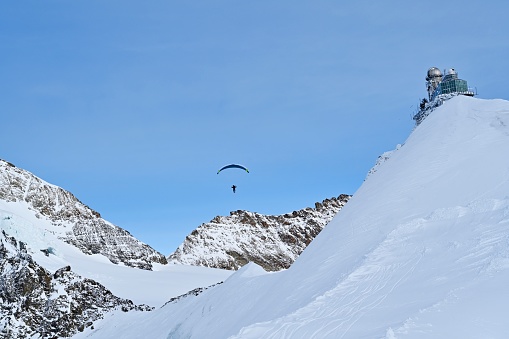 Paragliding in mountains, winter snow and red parachute.
