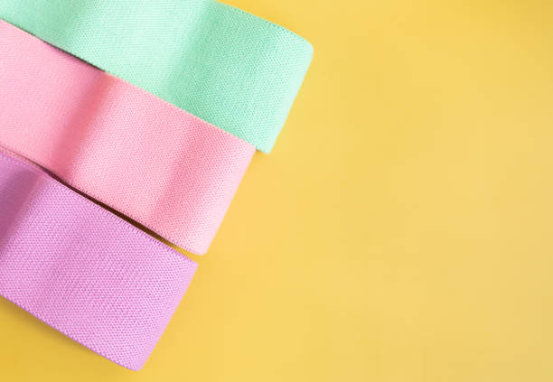 istock Home training concept - elastic bands on yellow background, flat lay. 1991781689