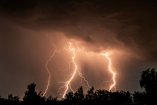 beautiful lightning during a thunderstorm at night in a forest that caused a fire, against a dark sky with rain