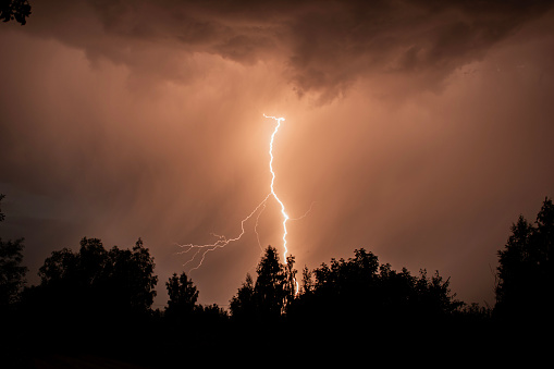 beautiful lightning during a thunderstorm at night in a forest that caused a fire, against a dark sky with rain