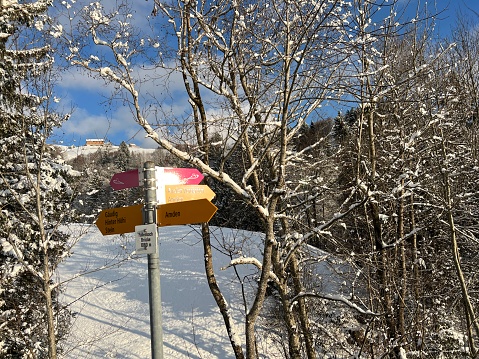 Hiking markings and orientation signs with signposts for navigating in the idyllic winter ambience over the Lake Walen or Lake Walenstadt (Walensee) and in the Swiss Alps, Amden - Switzerland (Schweiz)