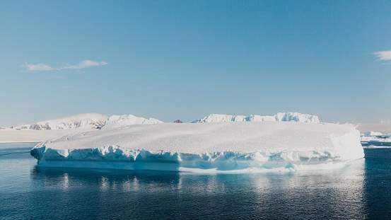 Large white Iceberg floating on the Antarctic Ocean at the coast of Antarctica Peninsula in the sun under sunny near cloudless sky. Antarctica Ocean, Coast of Antarctica.