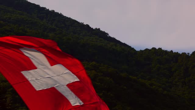 Skydiver Flying with a Hanging Swiss Flag and Mountain in a Sunny Day
