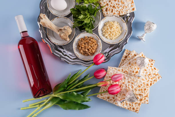 a beautiful dish with festive food for the jewish passover holiday. matzoth, nuts, lettuce, parsley, fruit paste. top view. blue background - passover matzo wine wine bottle стоковые фото и изображения