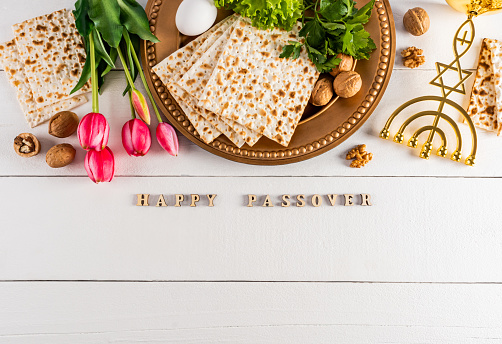 Festive background for the spring holiday of the Jewish Passover. Traditional foods, flowers, minor candlestick. Text of Happy Passover