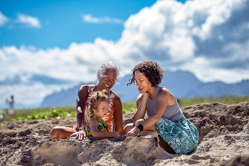 A cute Eurasian three year old girl playfully interacts with her mother and grandmother while sightseeing and enjoying nature in Hawaii.