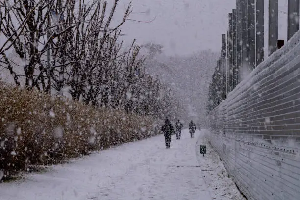 Photo of the city is hidden by white snow. people are walking outside. the architecture of the city is covered with snow