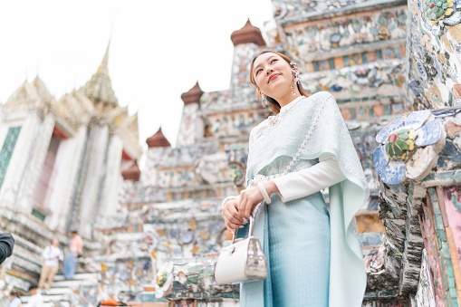 Young Asian woman exudes elegance and cultural pride in a stunning traditional Thai costume at the Temple of Dawn - Wat Arun.