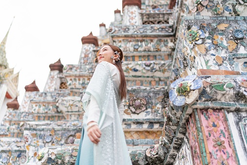 Young Asian woman exudes elegance and cultural pride in a stunning traditional Thai costume at the Temple of Dawn - Wat Arun.