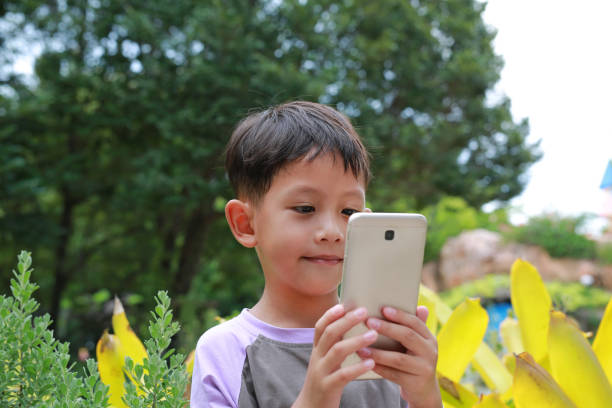 istock Cute Asian little boy child using smartphone outdoor. 1991877613