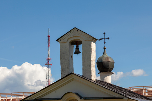 Bell of an ancient Orthodox white stone church against the sky.