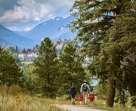 Grandfather, his daughter and her two children hiking in Estes Park, Colorado; hotel building and mountains in background