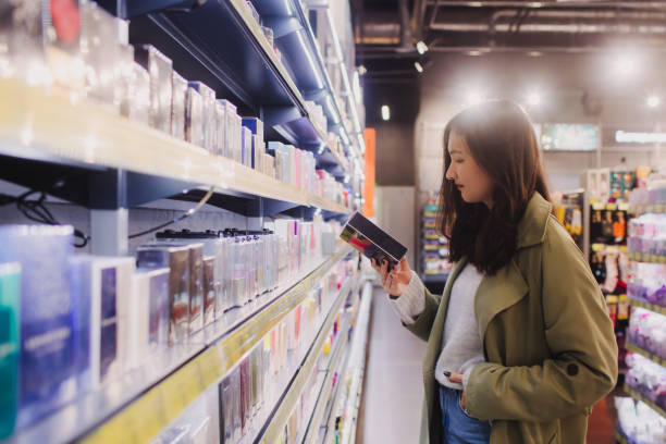 young girl shopping in retail store. beautiful teenage testing and buying cosmetics in a beauty store. side view. personal care and modern cosmetology. beauty and fashion. retail and consumerism. - asian ethnicity women shopping mall perfume - fotografias e filmes do acervo