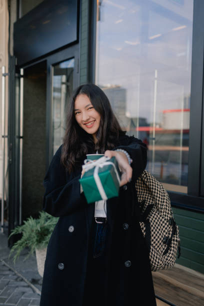 portrait d’une jolie fille coréenne tenant une boîte-cadeau et buvant un café dans un café près de la fenêtre. adolescente marchant dans la ville et s’amusant - red text messaging cafe teenage girls photos et images de collection