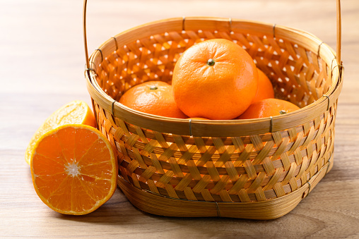 Mandarin orange fruit in basket on wooden background, Tropical fruit