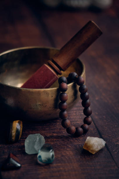 Tibetan bowl with rosary beads and gems on a dark background