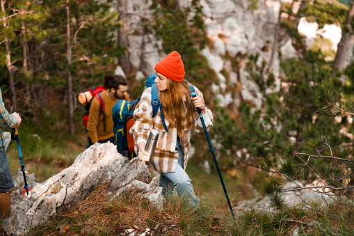 Young female hiker moving up the rocky mountain while her friends are in the background.