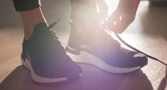 Young fitness woman tying shoelaces on sports shoe, getting ready for run