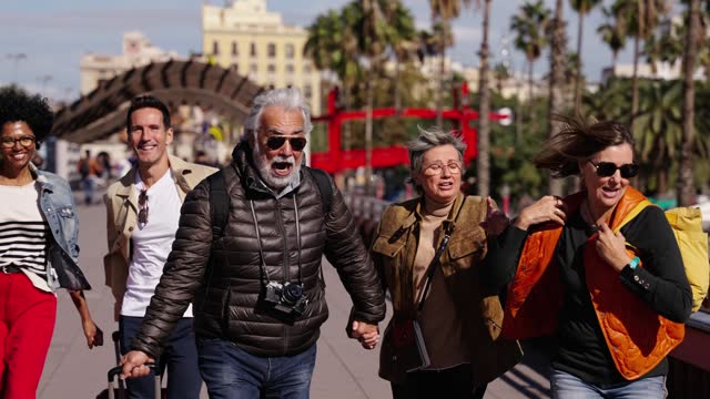 Group of middle-aged diverse tourist people running with their luggage down the street.