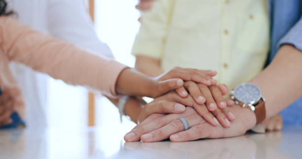 famiglia, mani giunte e tenuta con primo piano in casa per fiducia, sostegno e cura. uomo, donna e bambini con mucchio per l'unità, la comunità o la collaborazione sul tavolo in cucina con la generazione per il futuro - 4 of a kind foto e immagini stock