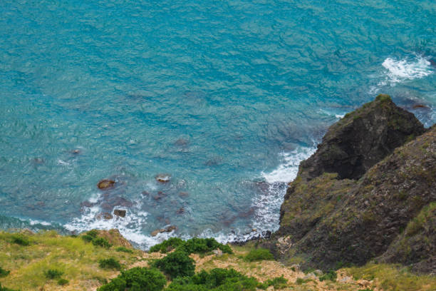 Large waves crash on the rocky shore view from above. Waves off the stone coast photo from a drone.