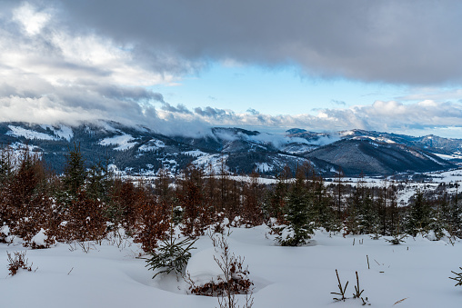 Surrounding of Nova Bystrica village in Slovakia during winter day with snow covered hills and blue sky with clouds