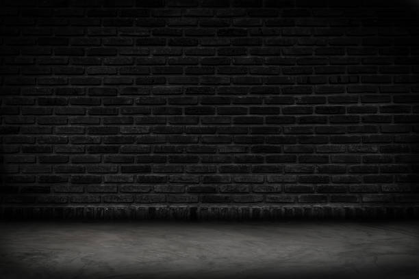 Empty black brick wall and concrete floor for background. Dark room interior with black brick wall blank cement floor for backdrop.