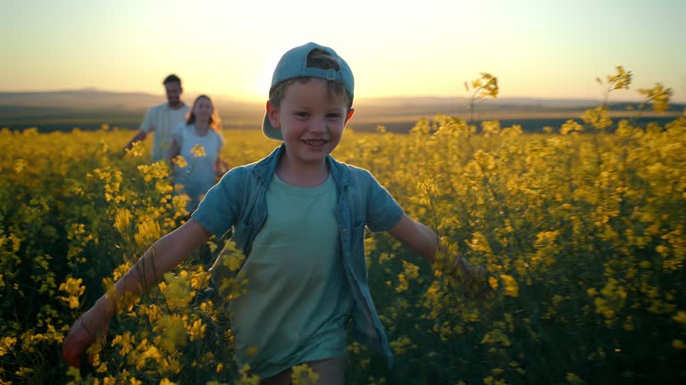 Freedom, countryside and boy running with his parents in a field of flowers while having fun during spring. Nature, energy or development with a son, mother and father outdoor as a family for bonding