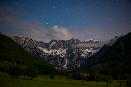 Zgornje Jezersko valley in Slovenia nighttime view with a starry night over the mountains  during a beautiful springtime night with the mountain range around the Grintovec mountain peak in the Kamnik–Savinja Alps.