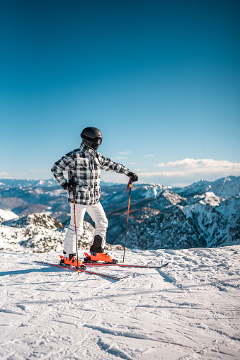 A mid adult Asian male is skiing on a snowy mountain slope. He is dressed in winter sports attire, including a helmet, goggles, and gloves, using ski poles and skis.
