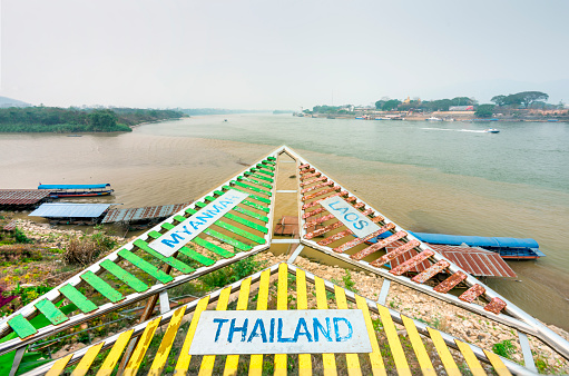Multi colored signage,for tourists,indicating the relevant locations of bordering countries of Thailand,Myanmar and Laos,making up the Golden Triangle,at the confluence of the Ruak and Mekong Rivers.