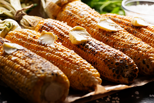Grilled sweetcorn cobs with butter on the table closeup low angle view