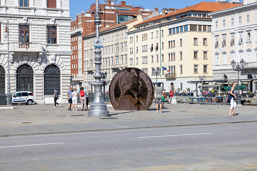 Trieste, Italy - September 26, 2023: Monument to the Austrian Thaler (thaler of Maria Teresa), great coin located on Ponterosso Square over Grand Canal