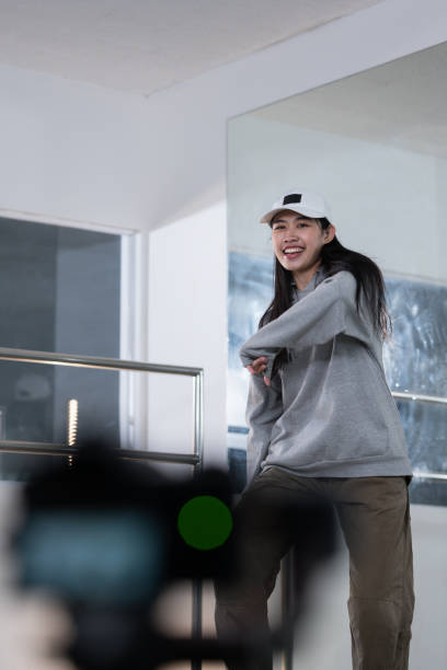 Cheerful young woman recording dance video tutorial for social media in studio