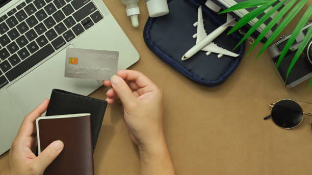 Top view of woman hand holding credit card with travel accessories and passport on desk. Traveling concepts Top view of woman hand holding credit card with travel accessories and passport on desk. Traveling concepts. discover card stock pictures, royalty-free photos & images