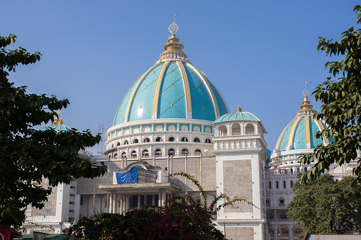 Mayapur, Nadia, India - January 27th 2024: The view of building of ongoing construction of Chandrodaya ISKCON temple of Mayapur through green trees