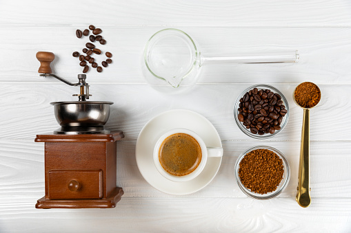 Ingredients for making coffee. Moka pot, Turkish coffee pots (cezve), coffee grinder with coffee beans, milk, sugar and spices on a white background. Drink preparation concept. Flat Lay.Copy space.
