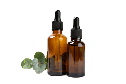 Eucalyptus essential oil in a glass bottle with green eucalyptus leaves on a textured wooden background. Aromatherapy concept. Spa. Natural organic ingredients for cosmetics and body care.Copy space