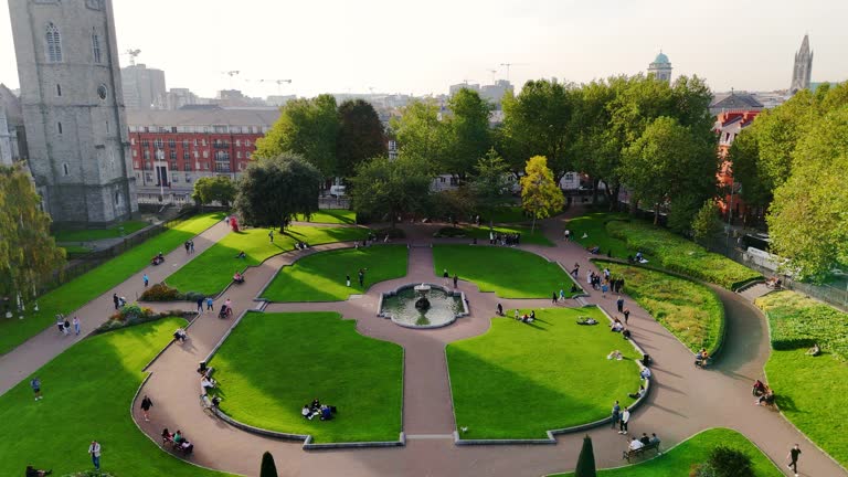 Aerial view of cathedral and park from Saint Patrick's Park-Dublin, Aerial view of historic St. Patrick's Cathedral in the heart of Ireland, Christ Church Cathedral, Aerial view of people walking in saint Patrick park, Public park fountain