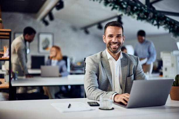 istock Elegantly dressed man, working at the office, colleagues working in the background. 1992064053