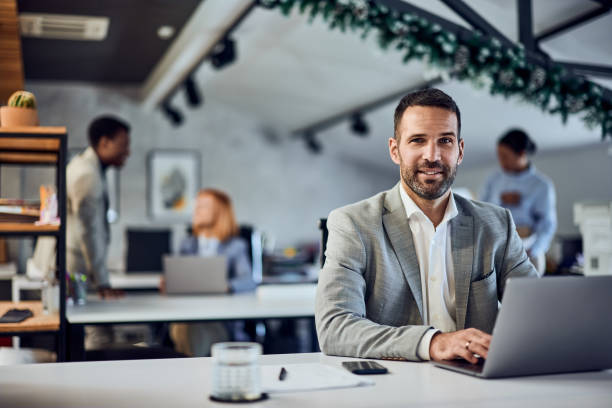 istock Portrait of a smiling man, posing for the camera, working in the co-working space, using a laptop. 1992064059