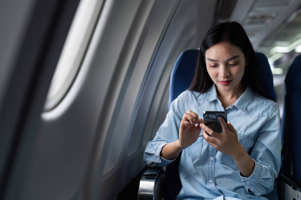 istock Asian people female person onboard, airplane window, using mobile while on the plane 1992069961