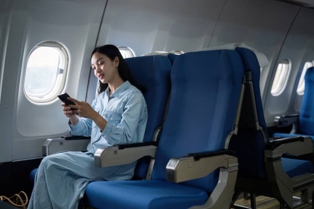 istock Asian people female person onboard, airplane window, using mobile while on the plane 1992070499