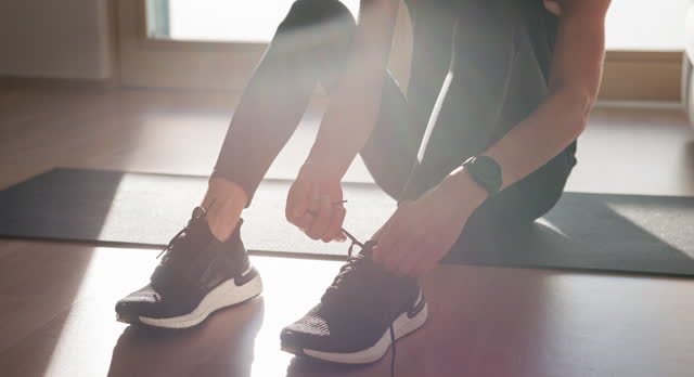 Woman adjusts shoelaces for indoor workout routine