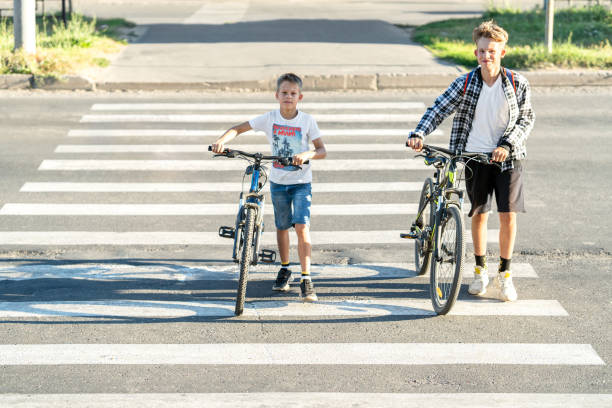 istock Two boys crossing pedestrian crosswalk with bicycles 1992087921